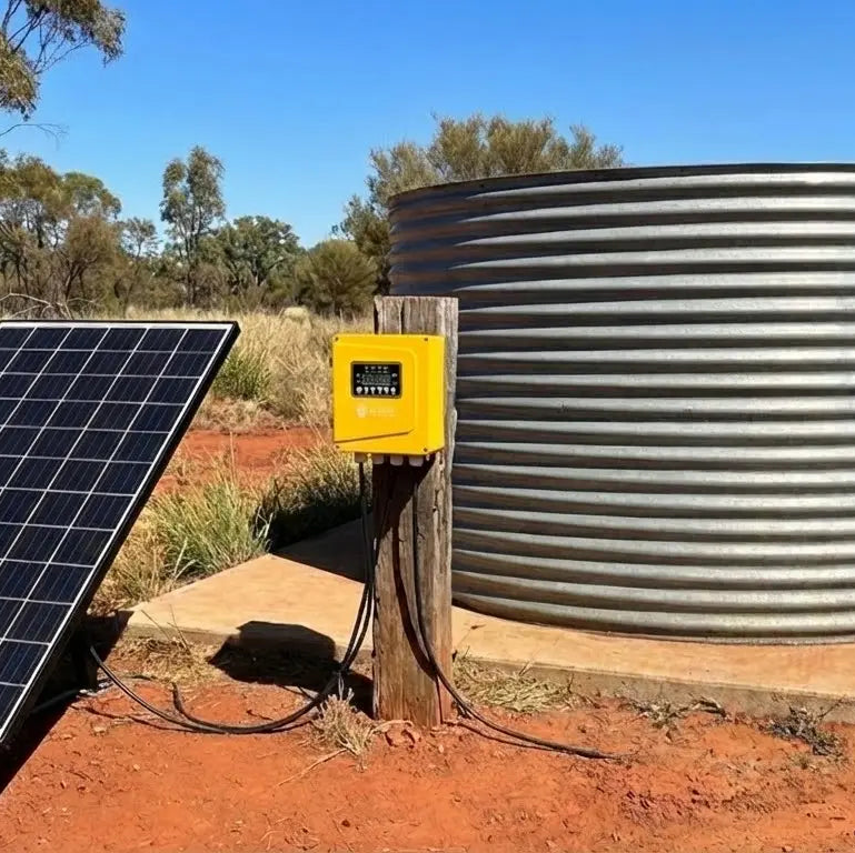 Solar panel and battery box next to a water tank in a rural setting